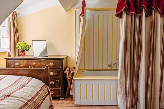 Swagged red curtain concealing the bathtub in the Single Room With Bath