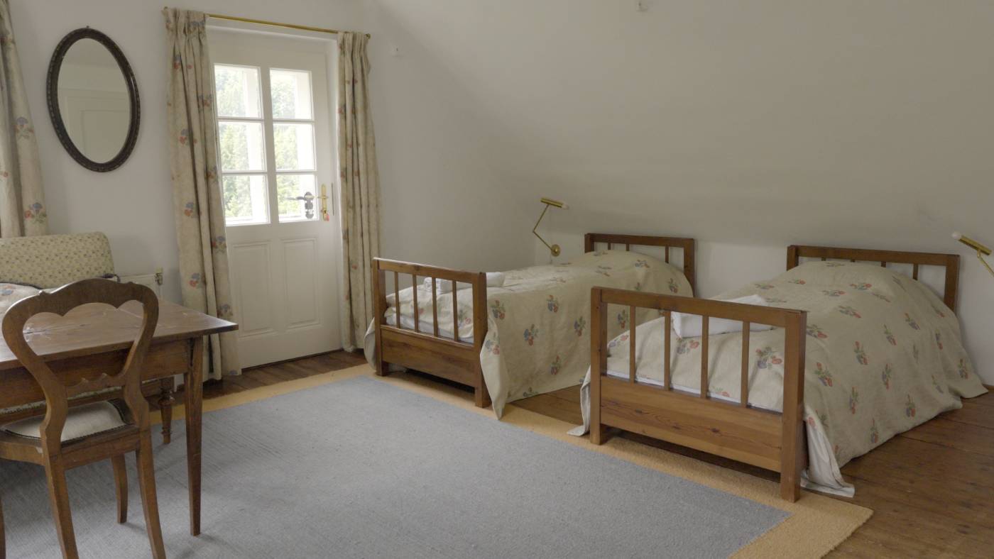 Twin pine beds beneath the eaves in the Twin Room With Balcony