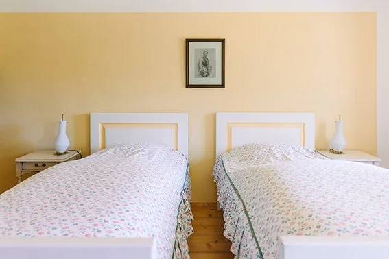 Twin beds against a butter-yellow wall in the Twin Room With Bathroom
