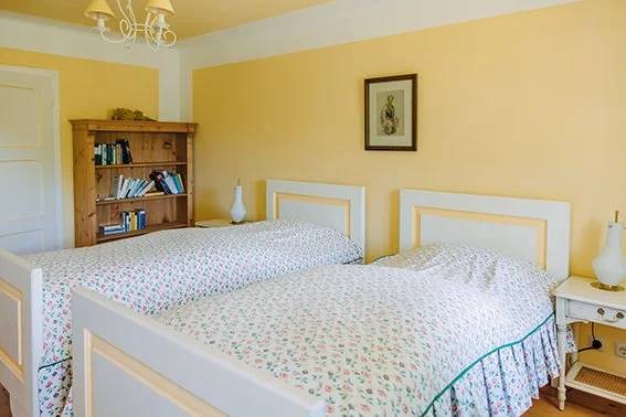 Floral bedspreads and a pine bookcase in the Twin Room With Bathroom